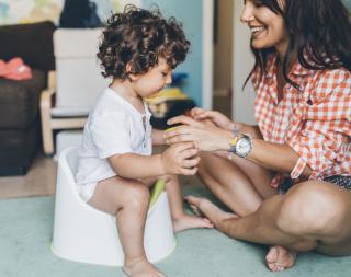 Mom helping her toddler son to learn how to use the potty. 