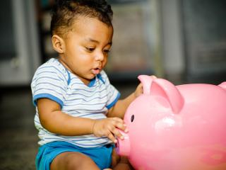 Baby looking at his piggy bank. 