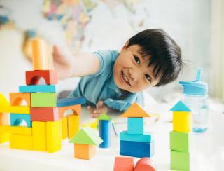 Happy little boy building with blocks. 