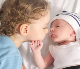 Loving toddler with his new born baby boy brother. 