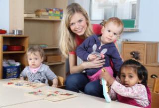 Childcare provider and three young children at the drawing table 