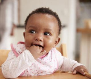 Cute Baby Girl Wearing Bib Sitting In High Chair 