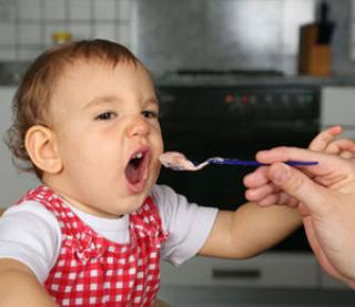 mother feeding baby girl, baby opens mouth wide 