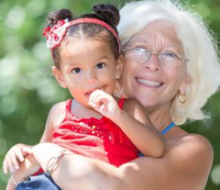 caucasian grandmother carrying her small latin granddaughter