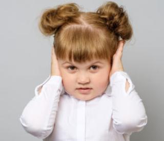 Disappointed little girl covering her ears isolated