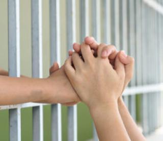 Mom holding kid hand at the back of the iron bar