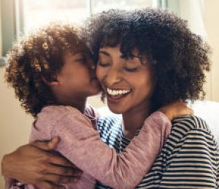 Shot of an adorable little boy kissing his mother on the cheek while bonding together at home