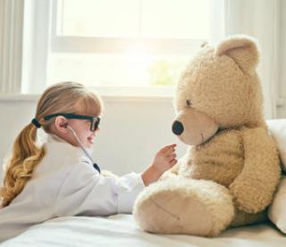 Shot of an adorable little girl dressed up as a doctor and examining a teddy bear with a stethoscope