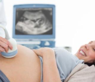 cropped image of doctor performing ultrasound on pregnant woman in clinic