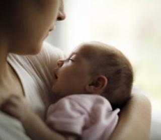 Mother holding her baby girl at home 