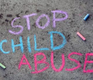 Colorful chalk drawing on asphalt: words STOP CHILD ABUSE