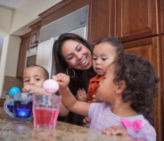 young family coloring easter eggs in kitchen