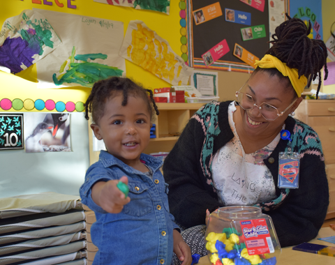 Parent and Child at Weinberg FSC Smailing toddler points at viewer as mom looks on