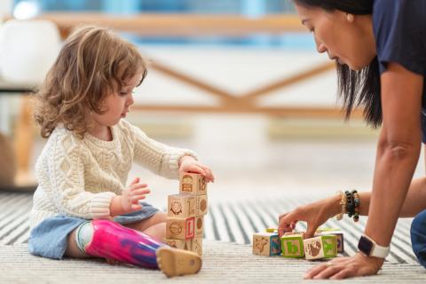 Little girl and child care provider playing with blocks. 