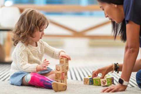 Special Needs Podcast Little girl and child care provider playing with blocks.