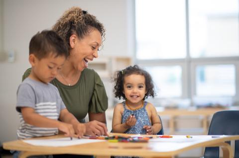 Child care provider and children joyously learning together. 