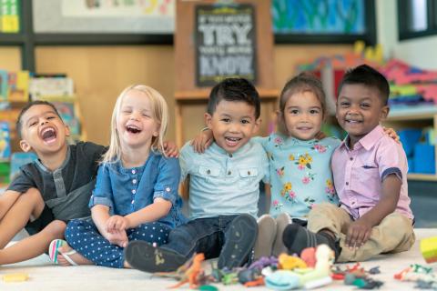 Multiracial group of smiling preschoolers.