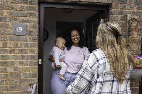 Family child care provider greats a mom at the door. 